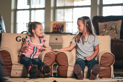 Two sisters sitting next to each other in child chairs