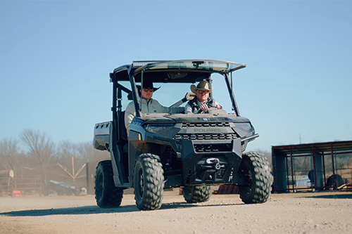 norris cattle company two men driving a ranger on farmland